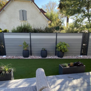 clôture composite gris clair basalte et écume Océwood. lame décorative verticale aluminium palme. poteaux gris foncé 7016.